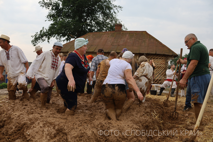 Мешканці Краснокутської громади місять глину для подальшого обліплення хати-мазанки