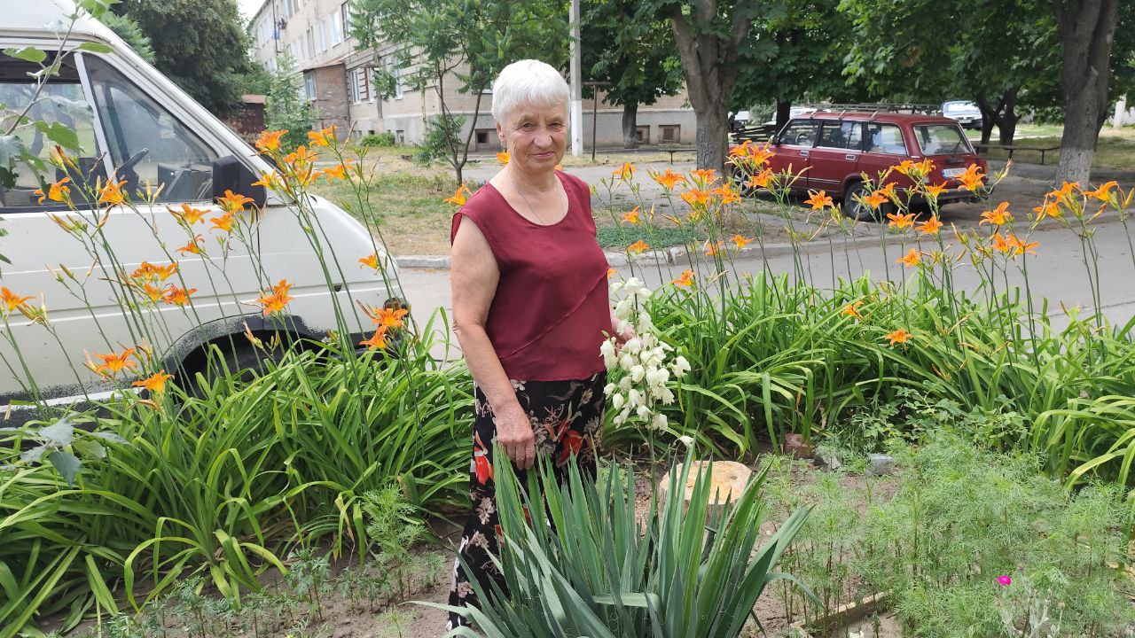 Жителька Балаклії посеред клумби, які засадила своїми руками